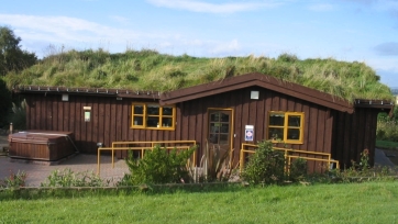 Picture of front of the Hytte - with grass roof - click for larger image. Opens in new tab